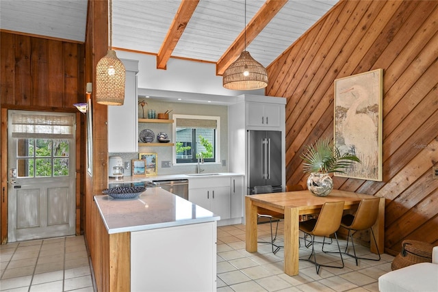 4365 S Atlantic Ave Unit B8, New Smyrna Beach, FL 32169 - kitchen with stainless steel appliances, a sink, light tile patterned floors, white cabinets, and wooden walls