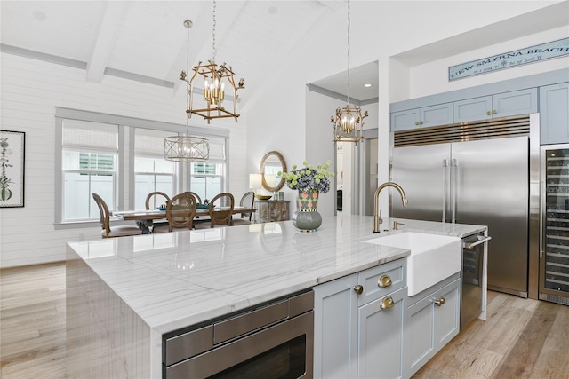 507 S Pine St, New Smyrna Beach, FL 32169 - kitchen featuring a chandelier, a sink, built in appliances, light wood-type flooring, and a large island with sink