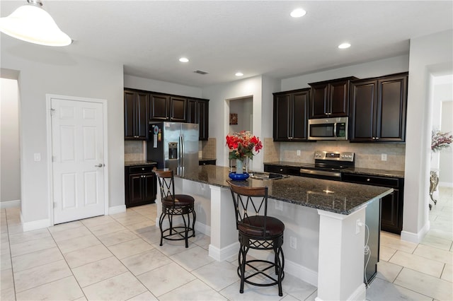 1431 Leitrim Loop, Apopka, FL 32703 - kitchen featuring stainless steel appliances, backsplash, a breakfast bar area, dark stone countertops, and recessed lighting