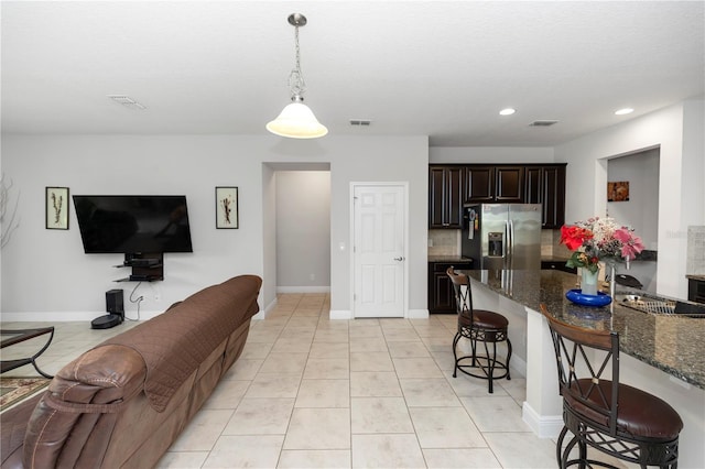 1431 Leitrim Loop, Apopka, FL 32703 - kitchen featuring stainless steel refrigerator with ice dispenser, open floor plan, a breakfast bar, dark stone counters, and dark brown cabinets