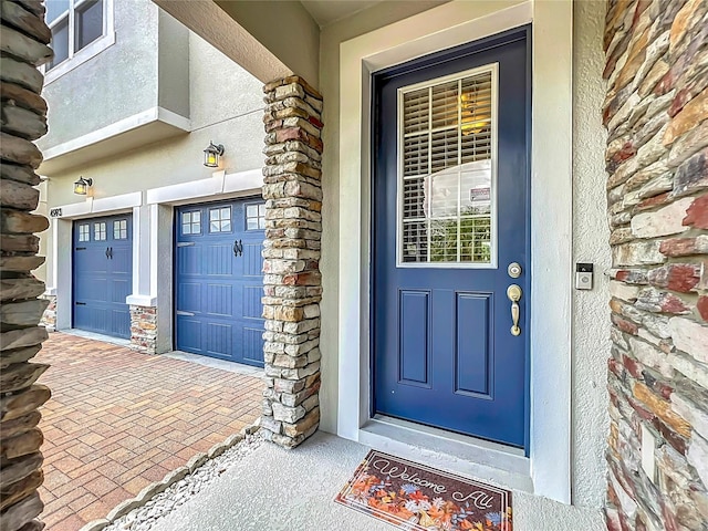 4993 Southlawn Ave, Orlando, FL 32811 - doorway to property featuring stone siding, stucco siding, an attached garage, and decorative driveway