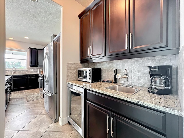 4993 Southlawn Ave, Orlando, FL 32811 - kitchen with a sink, freestanding refrigerator, beverage cooler, a textured ceiling, and decorative backsplash