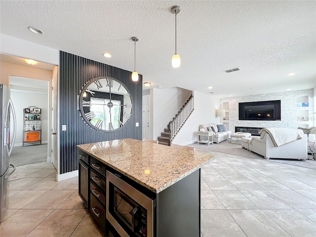 4993 Southlawn Ave, Orlando, FL 32811 - kitchen with appliances with stainless steel finishes, light tile patterned floors, a textured ceiling, hanging light fixtures, and a center island