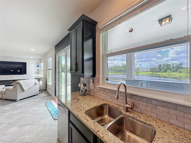 4993 Southlawn Ave, Orlando, FL 32811 - kitchen with a sink, a textured ceiling, dishwasher, tasteful backsplash, and light stone counters