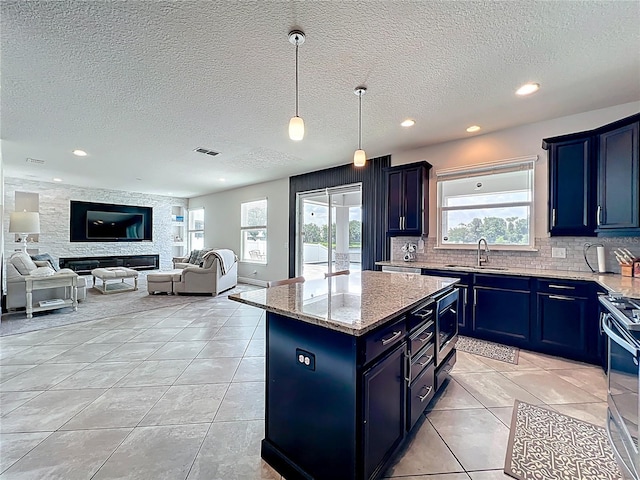 4993 Southlawn Ave, Orlando, FL 32811 - kitchen with blue cabinetry, a textured ceiling, a center island, light tile patterned flooring, and light stone countertops