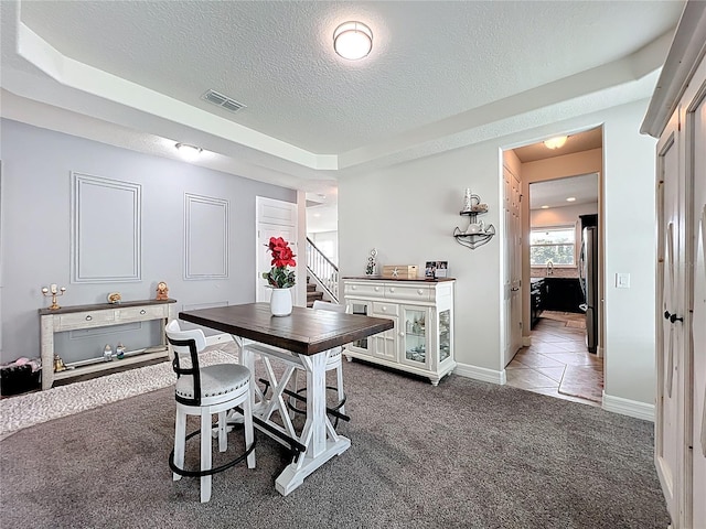 4993 Southlawn Ave, Orlando, FL 32811 - tiled dining area featuring carpet flooring, a textured ceiling, stairs, and baseboards