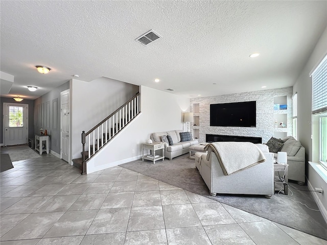 4993 Southlawn Ave, Orlando, FL 32811 - living area featuring baseboards, tile patterned floors, stairway, a textured ceiling, and a fireplace