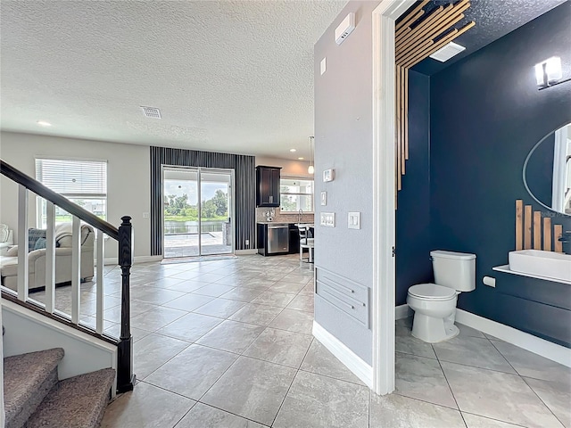 4993 Southlawn Ave, Orlando, FL 32811 - hallway with stairway, a textured ceiling, light tile patterned floors, and baseboards