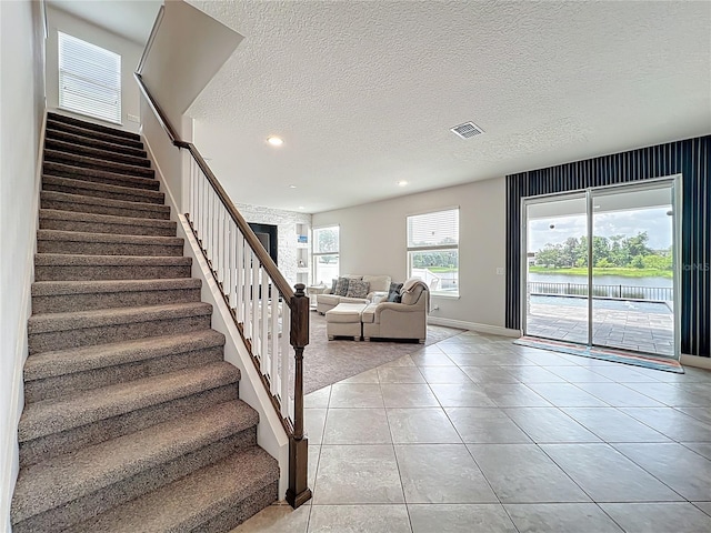4993 Southlawn Ave, Orlando, FL 32811 - staircase featuring tile patterned flooring, baseboards, a textured ceiling, recessed lighting, and a water view