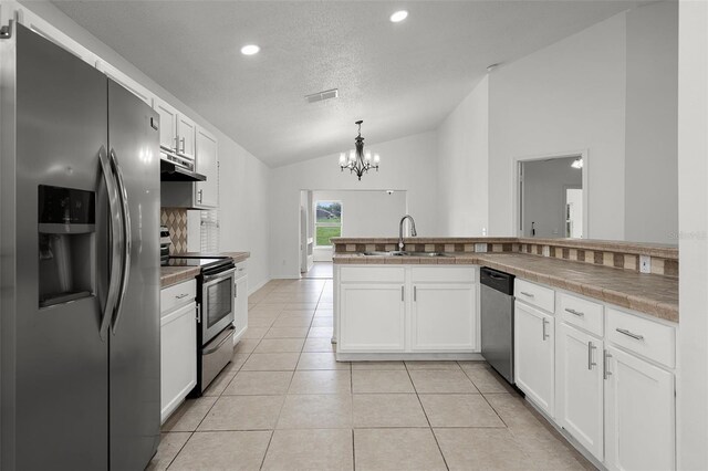 142 Stonegate Pass, Davenport, FL 33897 - kitchen featuring stainless steel appliances, lofted ceiling, a sink, under cabinet range hood, and white cabinets