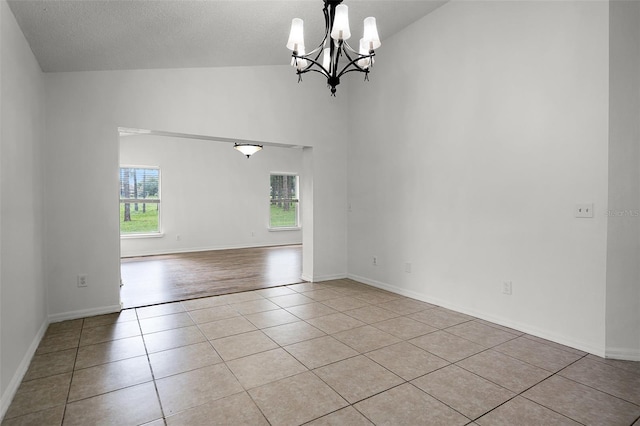 142 Stonegate Pass, Davenport, FL 33897 - tiled empty room with healthy amount of natural light, a chandelier, a textured ceiling, high vaulted ceiling, and baseboards