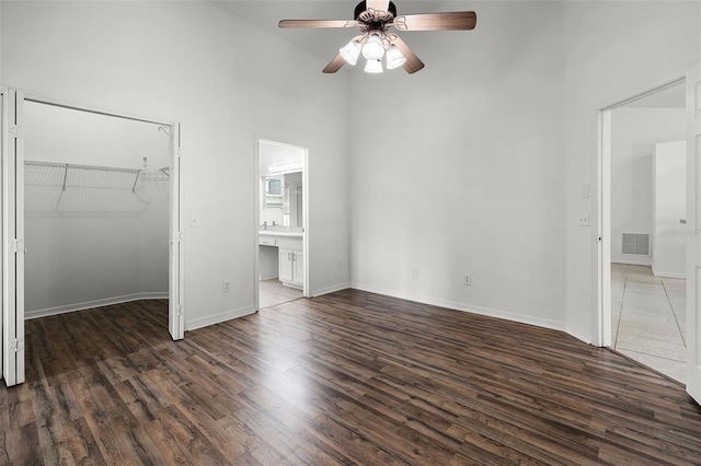 142 Stonegate Pass, Davenport, FL 33897 - unfurnished bedroom featuring wood finished floors, a towering ceiling, a spacious closet, baseboards, and connected bathroom