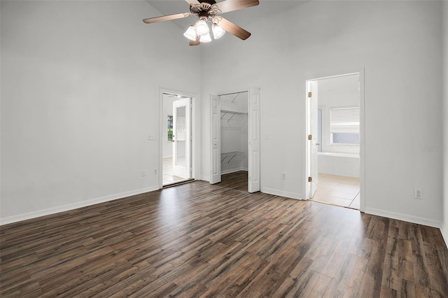 142 Stonegate Pass, Davenport, FL 33897 - unfurnished bedroom with a towering ceiling, dark wood-type flooring, a spacious closet, baseboards, and connected bathroom