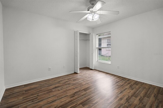 142 Stonegate Pass, Davenport, FL 33897 - unfurnished bedroom featuring dark wood-type flooring, a textured ceiling, a closet, baseboards, and a ceiling fan