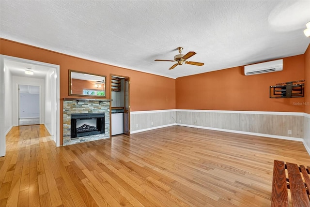 3637 Dubsdread Cir, Orlando, FL 32804 - unfurnished living room with a wall mounted AC, a textured ceiling, light wood-style flooring, ceiling fan, and a fireplace
