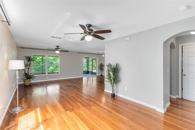 15324 Black Lion Way, Winter Garden, FL 34787 - unfurnished living room featuring arched walkways, light wood-style flooring, a ceiling fan, and baseboards