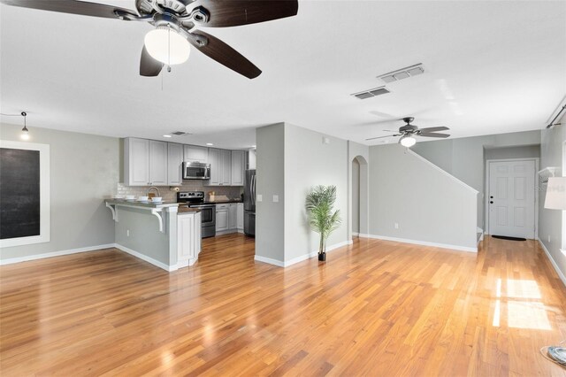 15324 Black Lion Way, Winter Garden, FL 34787 - unfurnished living room with ceiling fan, light wood finished floors, arched walkways, a sink, and baseboards