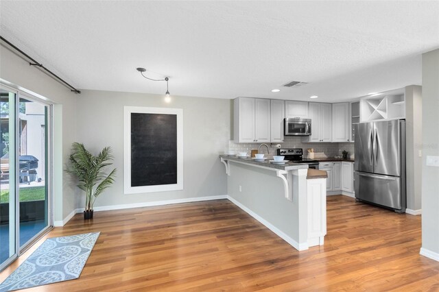 15324 Black Lion Way, Winter Garden, FL 34787 - kitchen featuring stainless steel appliances, a peninsula, decorative backsplash, open shelves, and a breakfast bar