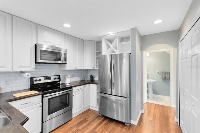 15324 Black Lion Way, Winter Garden, FL 34787 - kitchen with stainless steel appliances, dark countertops, arched walkways, tasteful backsplash, and recessed lighting