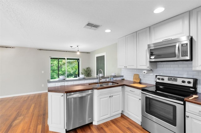 15324 Black Lion Way, Winter Garden, FL 34787 - kitchen featuring stainless steel appliances, a sink, wooden counters, a peninsula, and backsplash