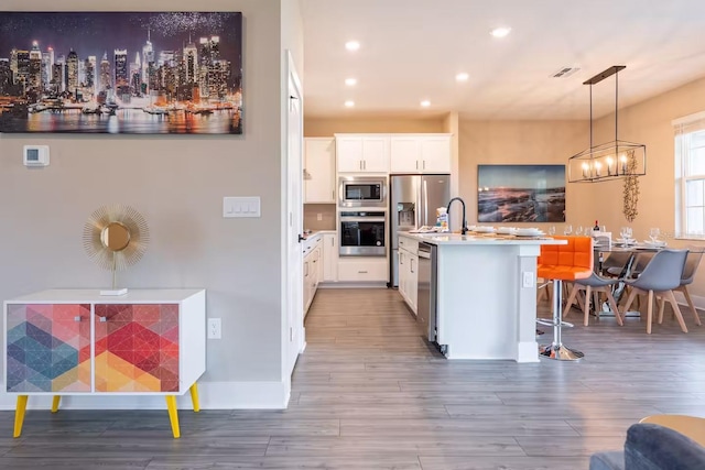 7951 Haverhill Way, Kissimmee, FL 34747 - kitchen featuring appliances with stainless steel finishes, wood finished floors, hanging light fixtures, white cabinets, and light countertops
