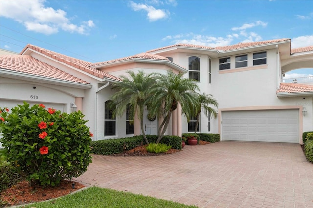 618 Manatee Bay Dr, Cape Canaveral, FL 32920 - mediterranean / spanish house featuring a tiled roof, a garage, decorative driveway, and stucco siding