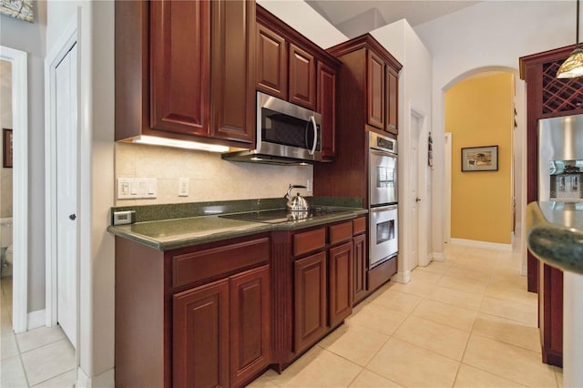 618 Manatee Bay Dr, Cape Canaveral, FL 32920 - kitchen with appliances with stainless steel finishes, dark countertops, light tile patterned floors, arched walkways, and tasteful backsplash