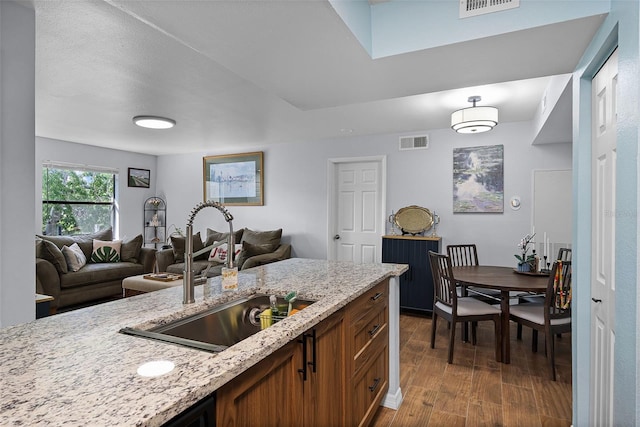3028 Parkway Blvd Unit 308, Kissimmee, FL 34747 - kitchen featuring a sink, dark wood-type flooring, light stone counters, open floor plan, and brown cabinets