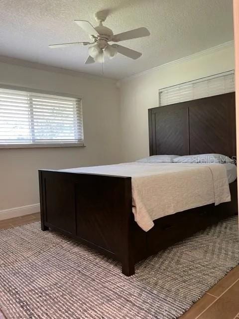 955 Gamewell Ave, Maitland, FL 32751 - bedroom with ornamental molding, a textured ceiling, ceiling fan, baseboards, and wood finished floors