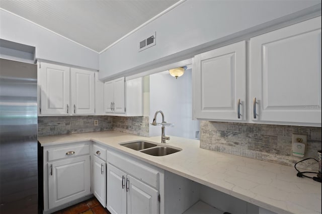 4420 Conway Gardens Rd, Orlando, FL 32806 - kitchen featuring stainless steel fridge, a sink, vaulted ceiling, white cabinetry, and tasteful backsplash