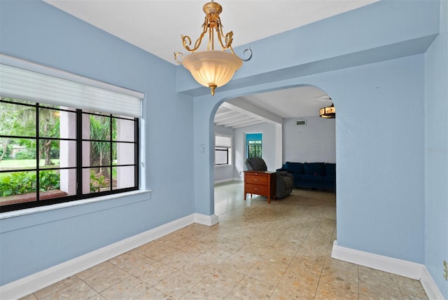 4420 Conway Gardens Rd, Orlando, FL 32806 - empty room featuring arched walkways, baseboards, beamed ceiling, and light tile patterned floors