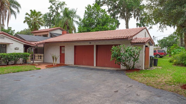 4420 Conway Gardens Rd, Orlando, FL 32806 - mediterranean / spanish-style home featuring an attached garage, a tiled roof, asphalt driveway, and stucco siding
