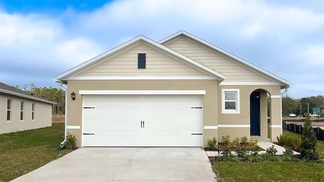 view of front facade with driveway, stucco siding, a front lawn, and a garage