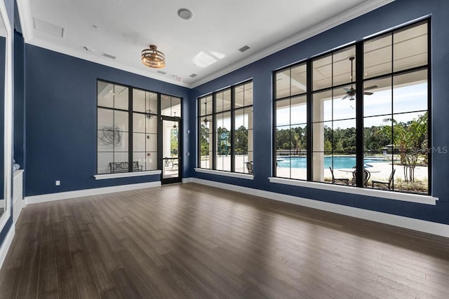 empty room with crown molding, baseboards, and wood finished floors