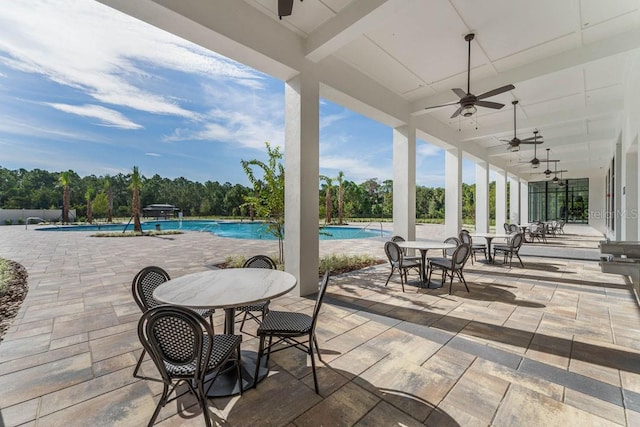 view of patio / terrace with ceiling fan, a community pool, view of scattered trees, and outdoor dining area