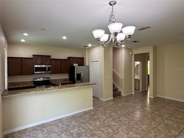 11187 Savannah Landing Cir, Orlando, FL 32832 - kitchen featuring stainless steel appliances, a chandelier, dark brown cabinetry, dark stone countertops, and light tile patterned floors