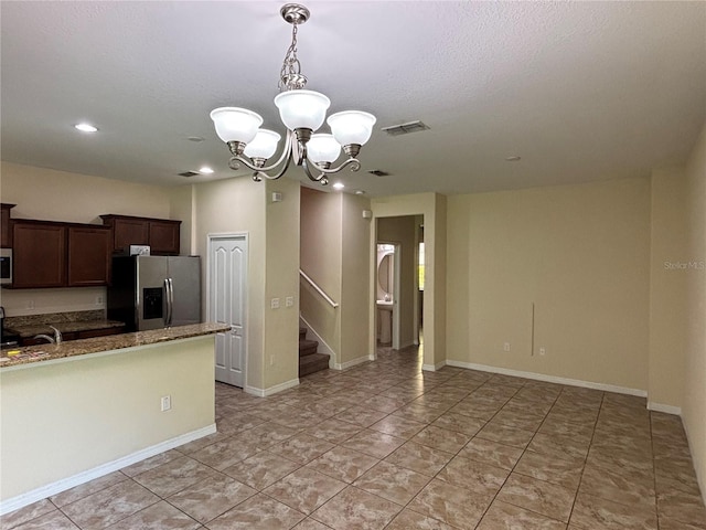 11187 Savannah Landing Cir, Orlando, FL 32832 - kitchen featuring appliances with stainless steel finishes, a chandelier, pendant lighting, dark brown cabinetry, and dark stone counters