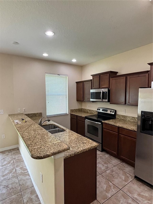 11187 Savannah Landing Cir, Orlando, FL 32832 - kitchen with stainless steel appliances, a sink, dark brown cabinets, a peninsula, and light tile patterned floors