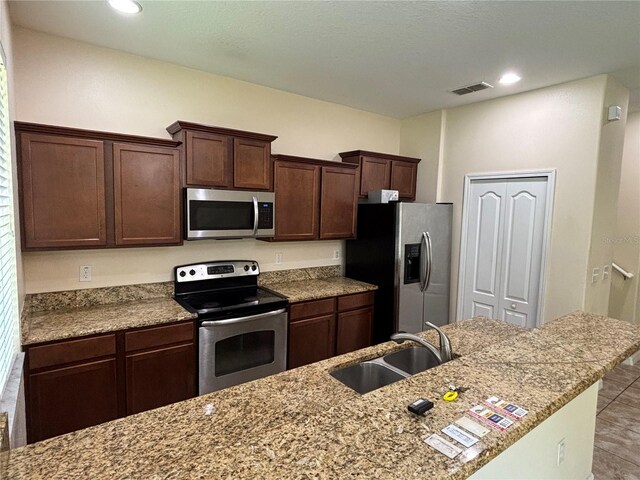 11187 Savannah Landing Cir, Orlando, FL 32832 - kitchen featuring stainless steel appliances, a sink, dark brown cabinets, light stone counters, and recessed lighting