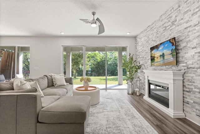 2340 Standing Rock Cir, Oakland, FL 34787 - living room with a ceiling fan, healthy amount of natural light, wood finished floors, a glass covered fireplace, and a textured ceiling
