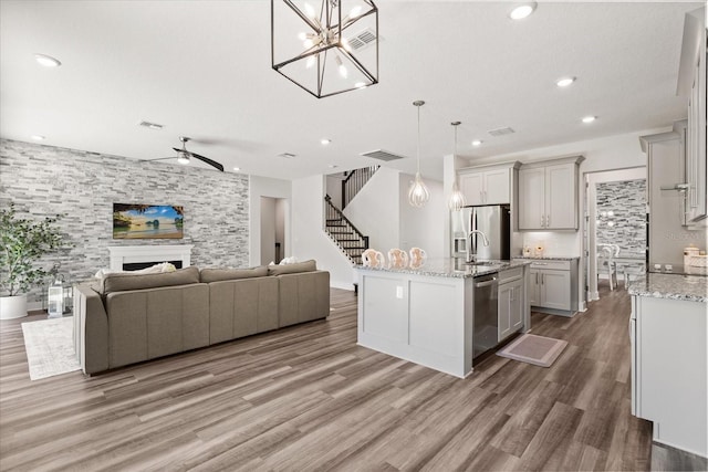 2340 Standing Rock Cir, Oakland, FL 34787 - kitchen featuring stainless steel appliances, open floor plan, ceiling fan, light wood-style flooring, and a fireplace