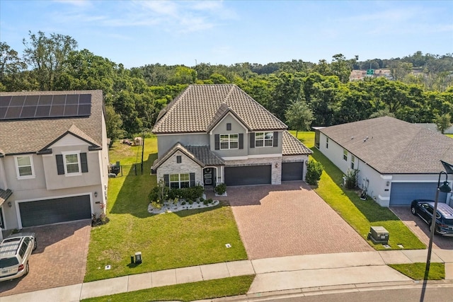 2340 Standing Rock Cir, Oakland, FL 34787 - view of front of house with stone siding, decorative driveway, an attached garage, a tiled roof, and stucco siding