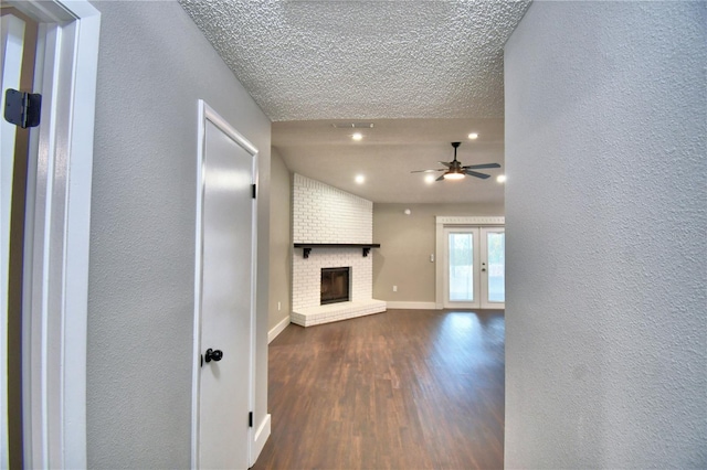 7504 Willow Wisp Dr E, Lakeland, FL 33810 - unfurnished living room with dark wood-style flooring, ceiling fan, a fireplace, baseboards, and a textured ceiling