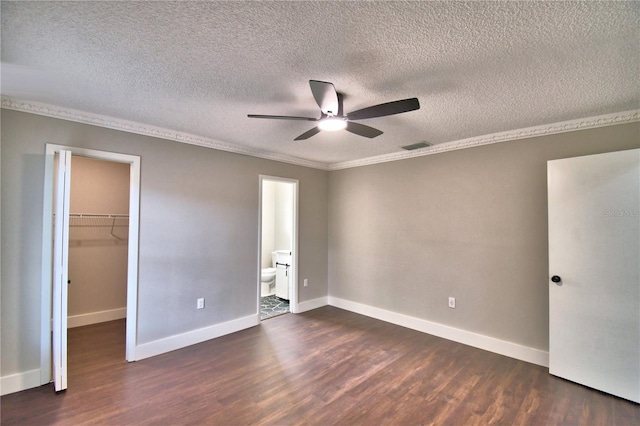 7504 Willow Wisp Dr E, Lakeland, FL 33810 - unfurnished bedroom with dark wood finished floors, a walk in closet, a textured ceiling, baseboards, and crown molding