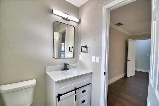 7504 Willow Wisp Dr E, Lakeland, FL 33810 - half bath with toilet, vanity, wood finished floors, crown molding, and a textured wall