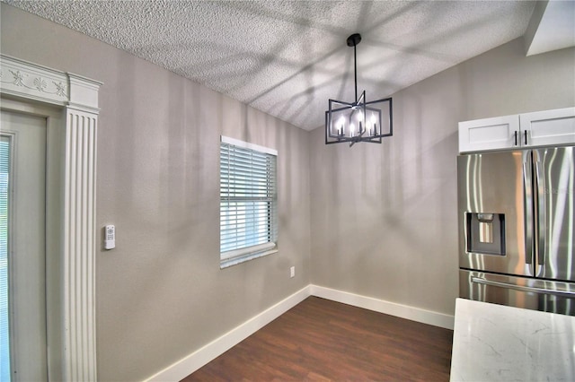 7504 Willow Wisp Dr E, Lakeland, FL 33810 - unfurnished dining area featuring baseboards, dark wood-style flooring, a textured ceiling, and a chandelier