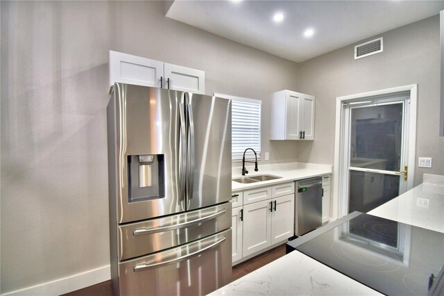 7504 Willow Wisp Dr E, Lakeland, FL 33810 - kitchen with appliances with stainless steel finishes, a sink, white cabinets, recessed lighting, and light stone counters
