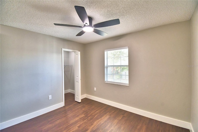7504 Willow Wisp Dr E, Lakeland, FL 33810 - unfurnished bedroom with dark wood-style floors, baseboards, a textured ceiling, a walk in closet, and a closet
