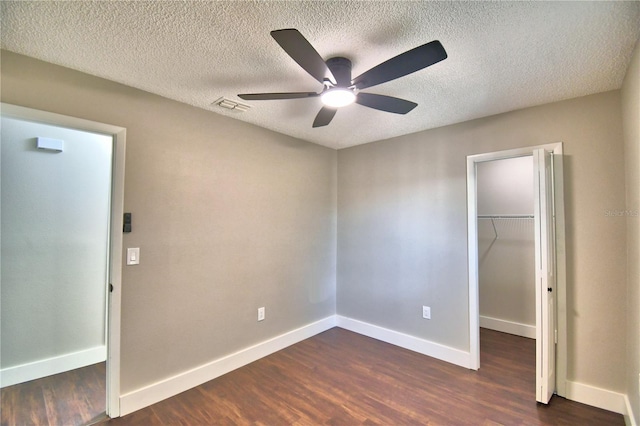 7504 Willow Wisp Dr E, Lakeland, FL 33810 - unfurnished bedroom with a walk in closet, a closet, dark wood-style floors, baseboards, and a textured ceiling