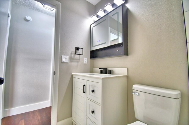 7504 Willow Wisp Dr E, Lakeland, FL 33810 - bathroom featuring vanity, wood finished floors, toilet, baseboards, and a textured wall